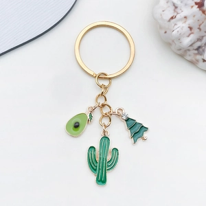 Détail de breloques en émail vert avocat et cactus sur un porte-clés doré élégant