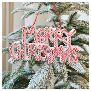 Close-up of Merry Christmas festive sign hanging on a snowy tree branch in red and white