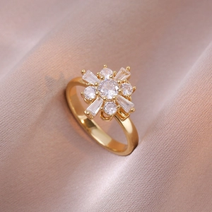 Elegant gold flower ring featuring clear zircon stones on soft pink silk background