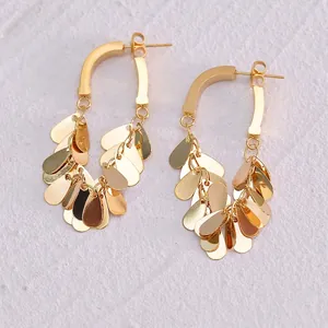 Détail de boucles d'oreilles bohèmes dorées avec pendentifs feuilles en couches