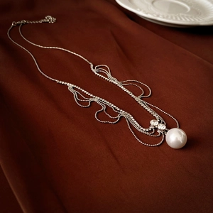 Detailed view of luxury silver tassel necklace with rhinestones and large round pearl