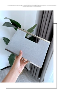 Detail showing hand holding silver rectangular clutch with woven texture and metal handle