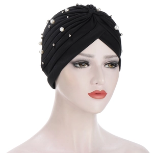 Detail of black turban hat with white pearls and beads on mannequins head
