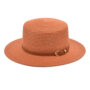 Detail of terracotta boater hat with woven texture and brown faux leather buckled strap