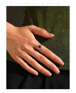 Macro shot of silver square rainbow gemstone ring with pavé diamond halo on model's finger