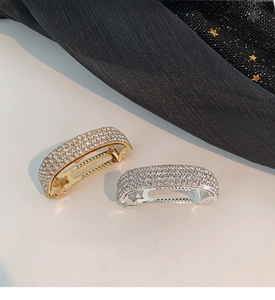 Close-up of gold and silver curved ponytail clips fully encrusted with sparkling rhinestones