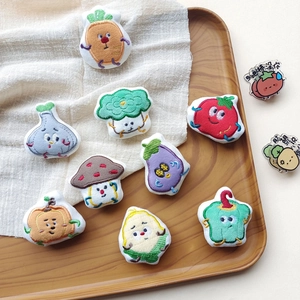 Plush cartoon vegetable and fruit doll brooches collection on a wooden tray
