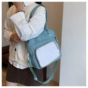 Detail of light blue crossbody bag featuring a transparent front pocket and mesh layer