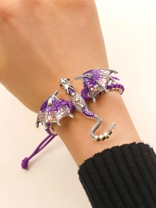 Detail van draakarmband met paarse emaille vleugels en kleurrijke strasstenen op gevlochten touw