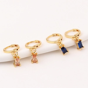 Makroaufnahme von goldenen Ohrringen mit rechteckigen rosa und blauen Zirkonia Steinen