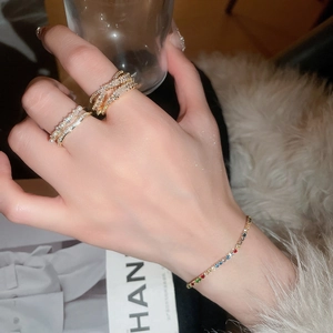 Detailed shot of gold-plated crossover rings and colorful zircon tennis bracelet on hand