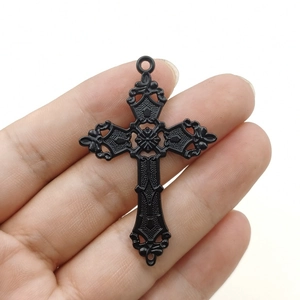 Close-up of a vintage antique silver cross pendant with intricate embossed floral patterns