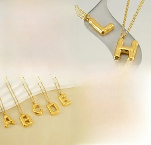 Detailed macro view of gold-plated balloon letter pendants made of polished stainless steel