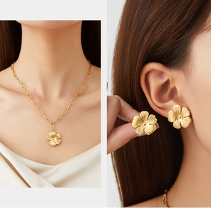 Detailed close-up of golden floral necklace and earrings with matte brushed finish