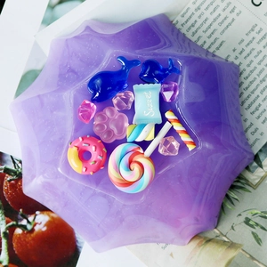 Assorted colorful resin charms like donuts and lollipops for DIY crafts in a star tray