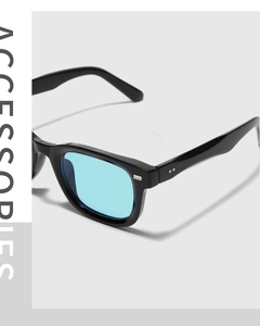 Detail of black square sunglasses with blue lenses and silver rivet accents