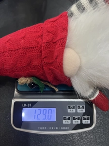 Detail shot showing a Christmas gnome doll weight of 129g on a digital scale