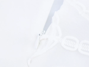 Détail d'une robe blanche avec fermeture éclair invisible et bordure en dentelle