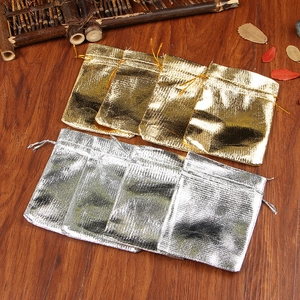 Macro shot of gold and silver drawstring jewelry pouches on a rustic wooden background