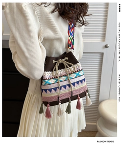 Close-up of ethnic bucket bag with colorful embroidery, tassels, and woven strap detail