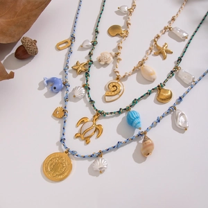 Detail of layered bohemian necklace with turtle, starfish, and pearl charms on woven rope