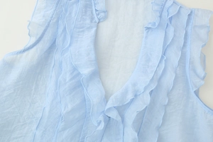 Detail of light blue sleeveless top featuring a ruffled V-neck and textured pleated fabric