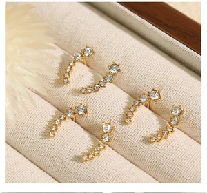 Macro shot of three pairs of golden curved stud earrings with cubic zirconia in a jewelry box