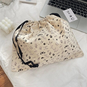 Close-up of beige canvas drawstring pouch with cat print on a minimalist desktop