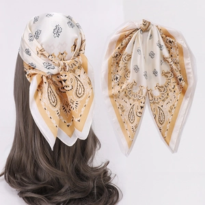 Detail of silk-like square scarf with yellow paisley print used as a hair headband