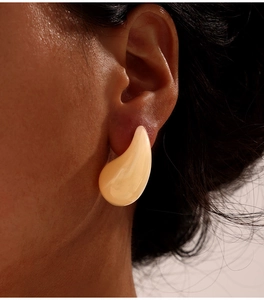 Gros plan détaillé de boucles d'oreilles goutte en résine crème portées par un mannequin