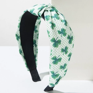 Knotted fabric headband with green clover and polka dot print on a white background