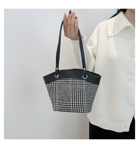 Detail of houndstooth canvas bucket bag with black leather trim and metal ring hardware