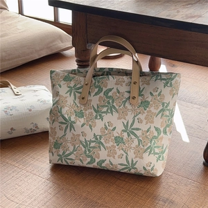 Floral canvas tote bag with leather handles shown on a wooden floor in a cozy room