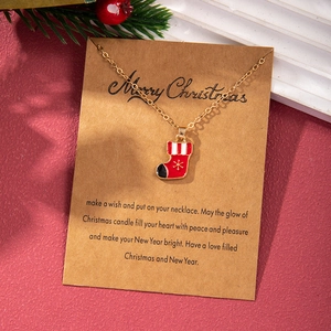 Christmas stocking necklace pendant on a kraft wish card with a golden chain on red background