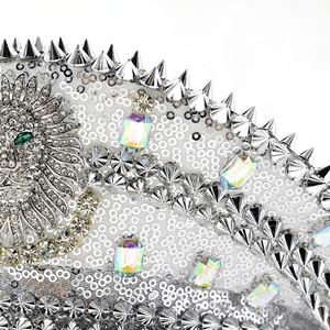Detailed macro of silver sequins, metal spikes, and a crystal-encrusted lion head emblem