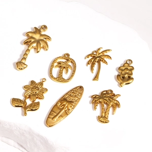 Gold titanium steel tropical pendants featuring palm trees and surfboards on white rock