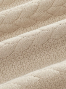 Macro shot of beige knit fabric with leaf jacquard texture and premium craftsmanship
