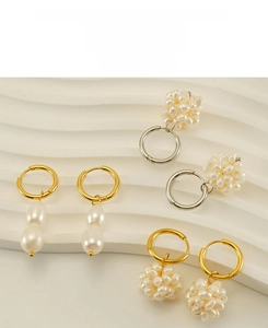 Détail de boucles d'oreilles en perles sur un présentoir beige aux formes ondulées