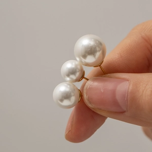 French vintage gold earrings with triple white pearls held in hand for close-up view