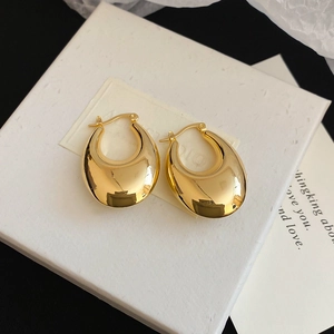 Detail of high-polished gold teardrop earrings on a textured jewelry card with fabric