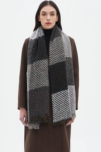 Detail shot of multicolor plaid scarf with fringes on brown coat model with grey tones