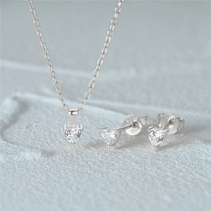 Close-up of S925 sterling silver heart-shaped necklace and stud earrings set on stone surface