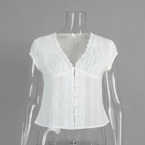 Detail of white V-neck blouse with lace trim, vertical texture and fabric buttons