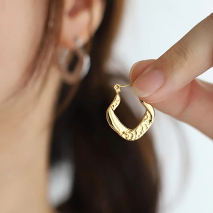 Macro view of gold horseshoe earrings featuring hammered texture and a glossy finish