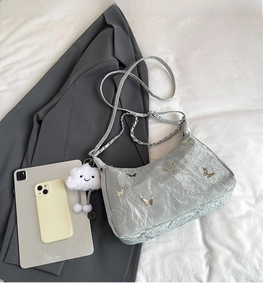 Light gray wrinkled shoulder bag with silver butterfly charm and chain strap detail