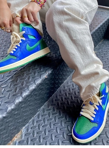 Détail de basket montante avec empiècements en cuir bleu et vert sur escalier industriel