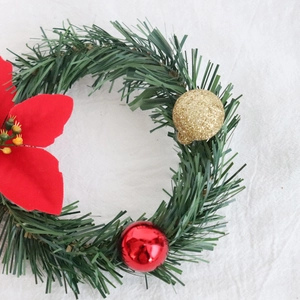 Close-up of artificial pine wreath with red poinsettia and glittering gold Christmas balls
