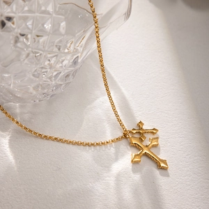 Primo piano della collana con pendente a croce dorata che riflette la luce naturale