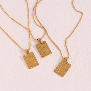 Detailed macro view of 18K gold plated rectangular pendants with textured water drop patterns