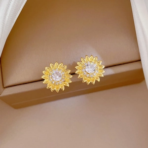 Detailed macro view of golden sunflower stud earrings with crystals on silk padding